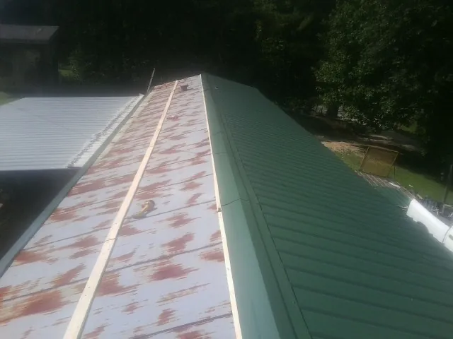 Old rusted panels beside newly installed green metal roofing — Wind Damage Roof Repair by Roofing Brothers in Chesterfield