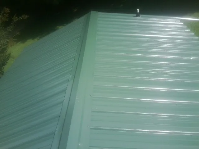New green metal panels meeting at the ridge of a roof — Flat Roof Repair work by our crew in Chesterfield