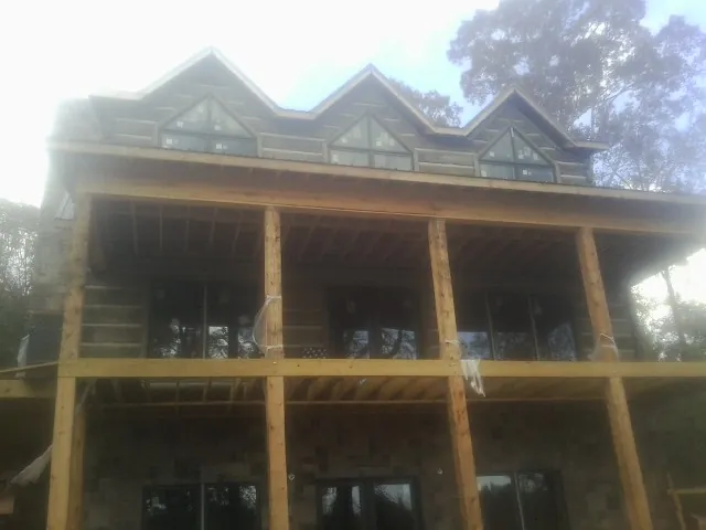 Dormers and porch framing on a large log home under construction — Roof Coating work by our crew in Chesterfield