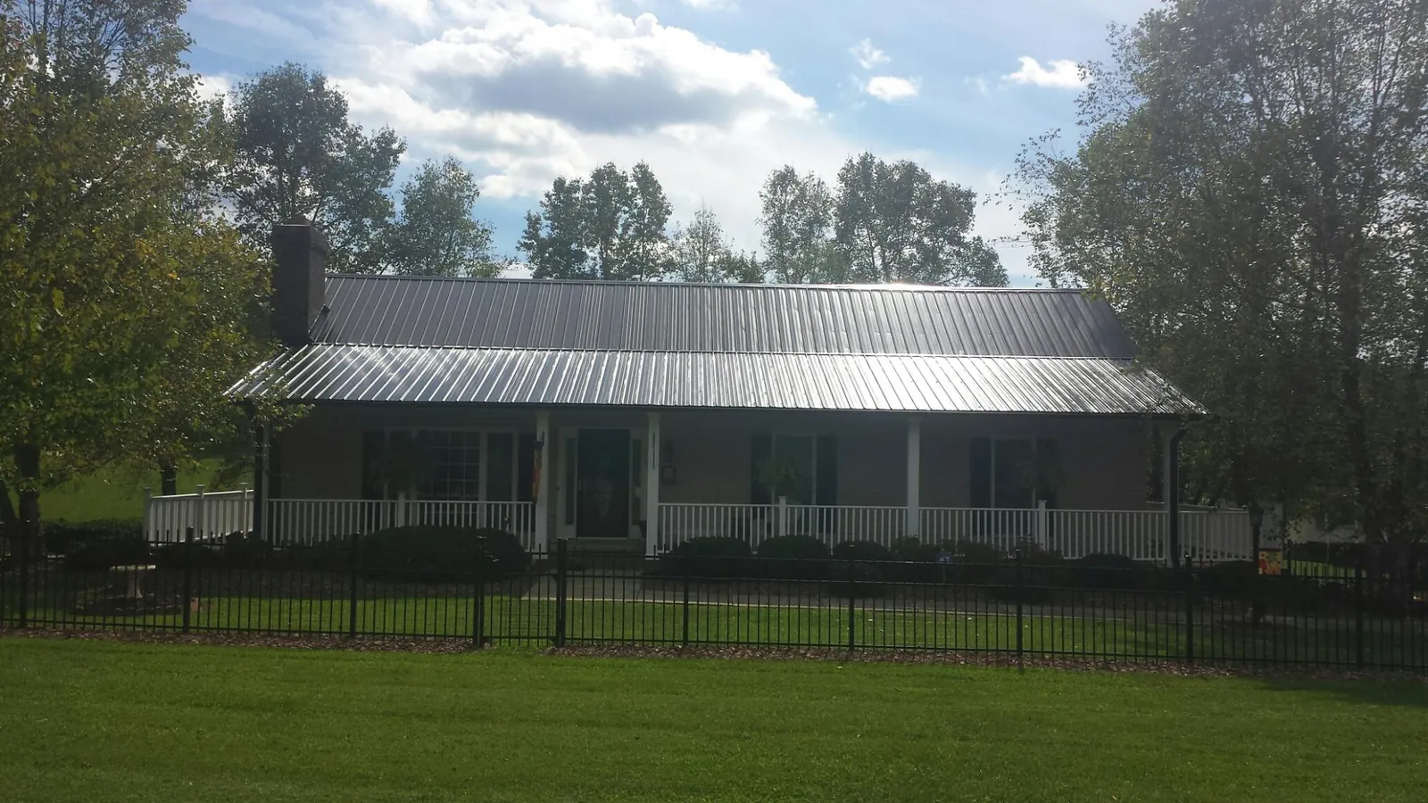 Gray metal roof on a brick ranch with a full width front porch — Gutter Guard Installation work by our crew in Chesterfield